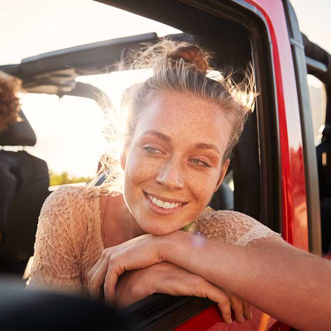 Frau guckt glücklich aus dem Autofenster